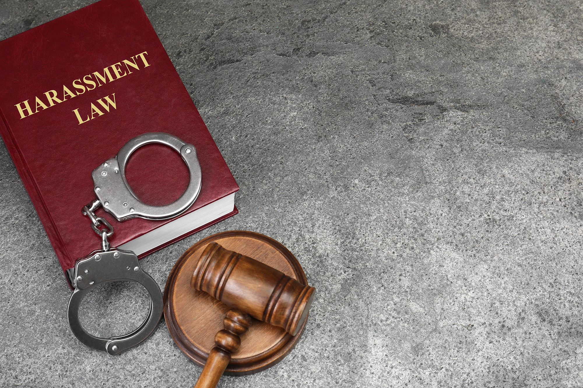 Handcuffs, a gavel, and a book on harassment law symbolizing the repercussions of a sexual crime