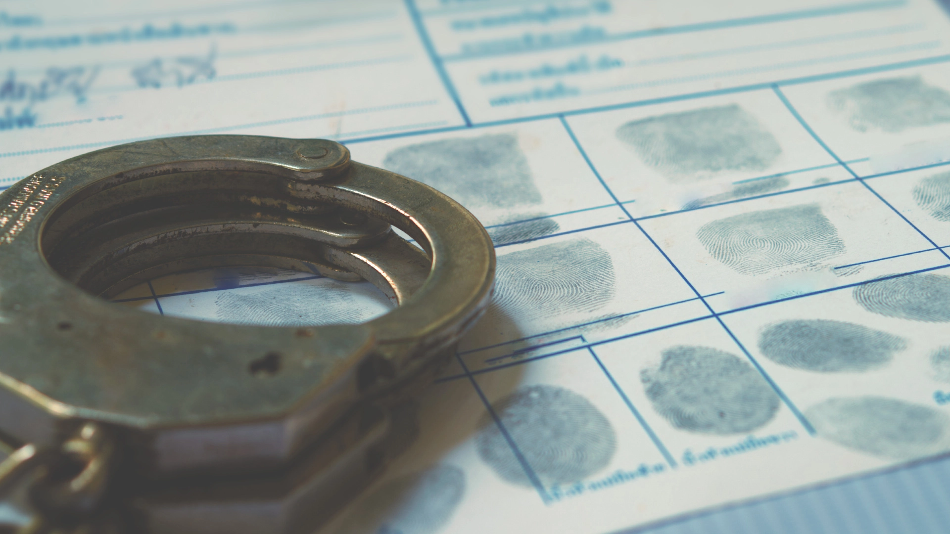 A pair of handcuffs lying on top of a criminal's fingerprints from a drug crime
