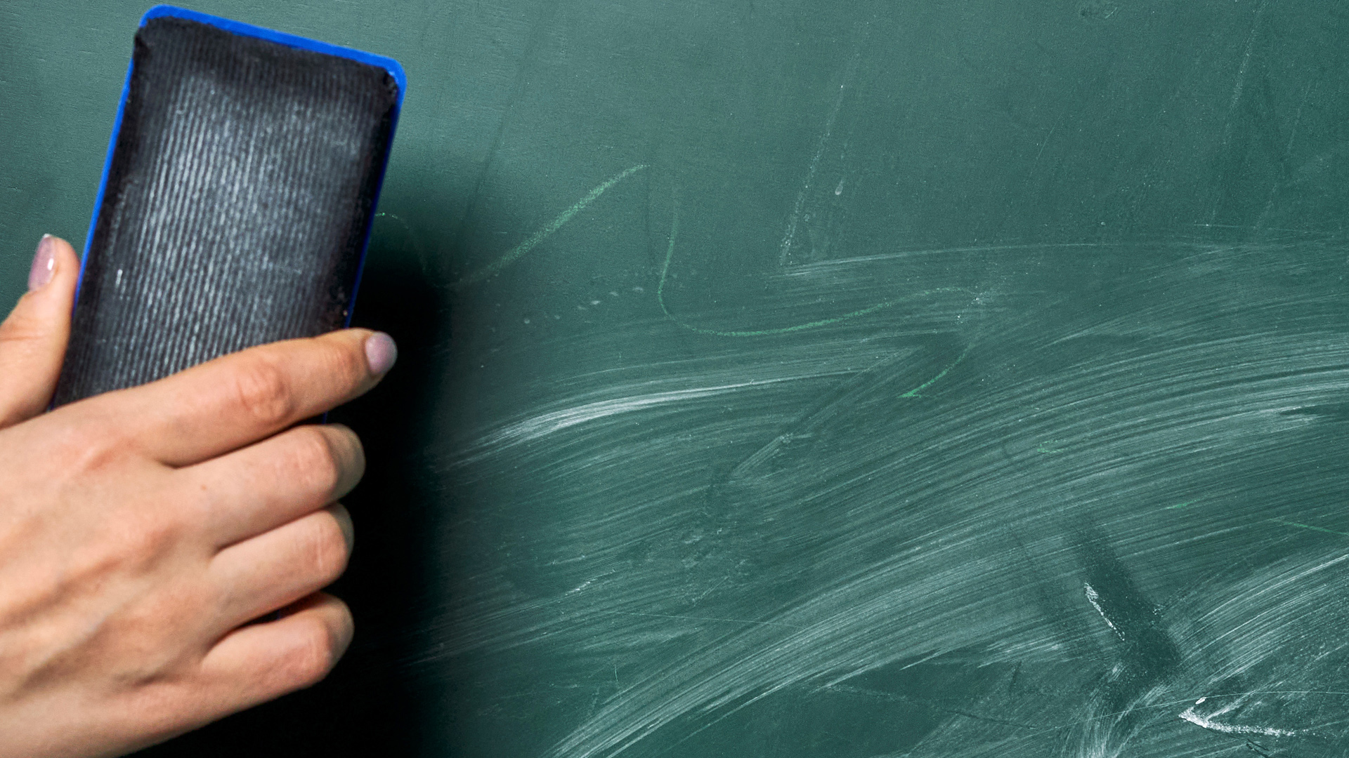 A person holding an eraser over a chalkboard representing the clean slate of an expungement