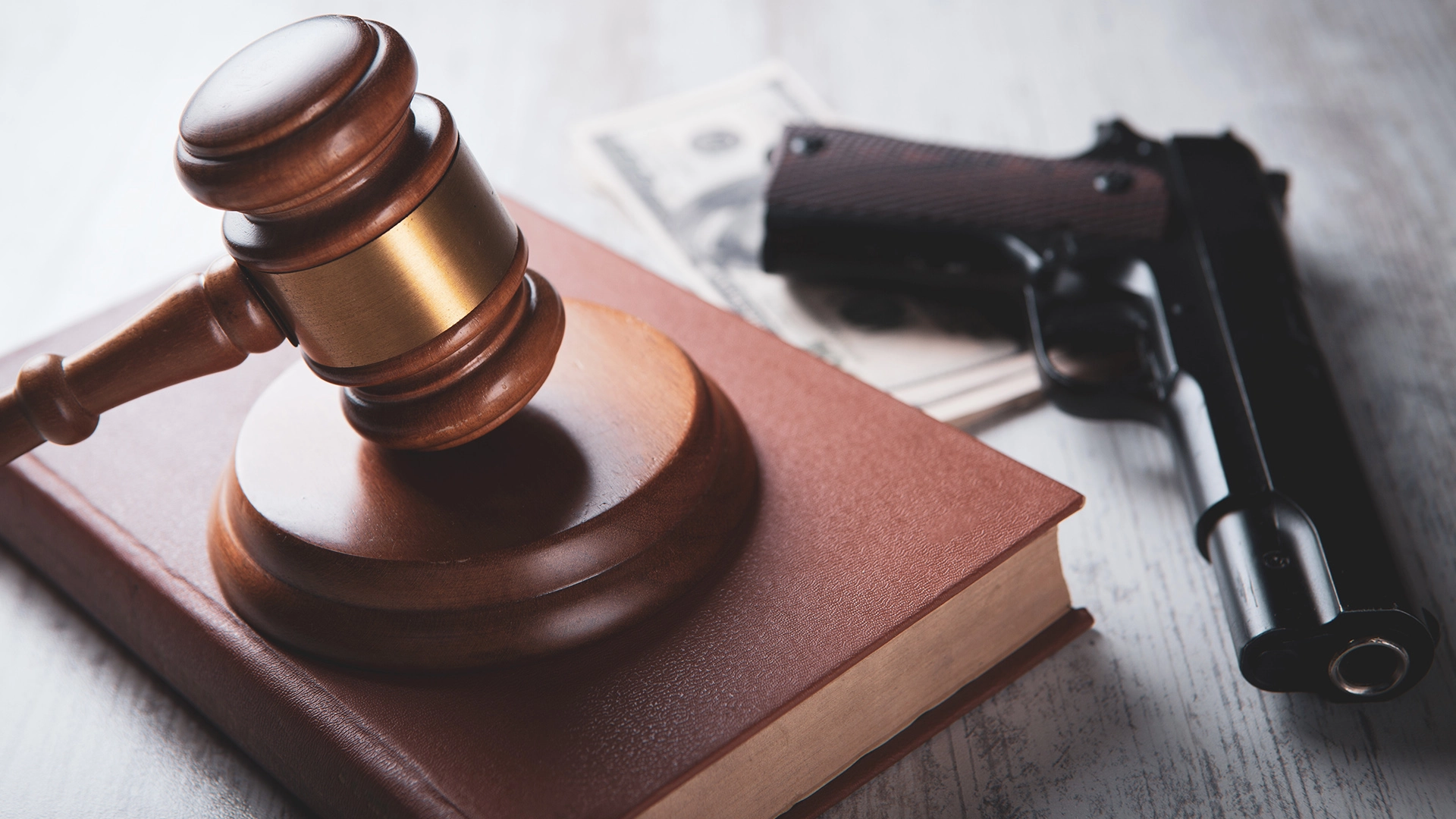 A pistol and law gavel together representing the repercussions of a violent crime